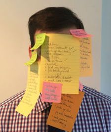 A man with post-it note over his face -- overcommitted 